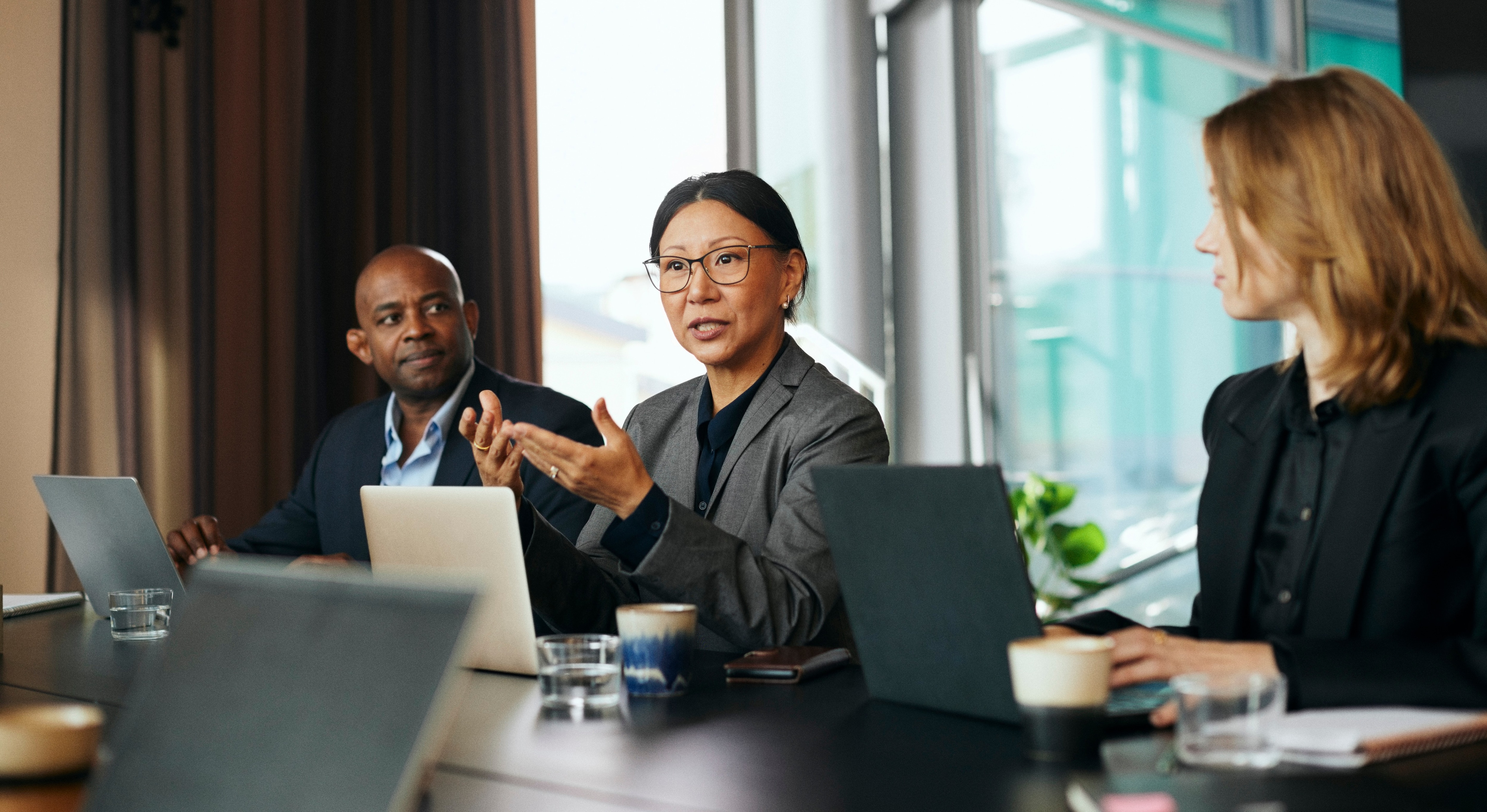 Mature businesswoman discussing with male and female colleagues during meeting in board room at office 