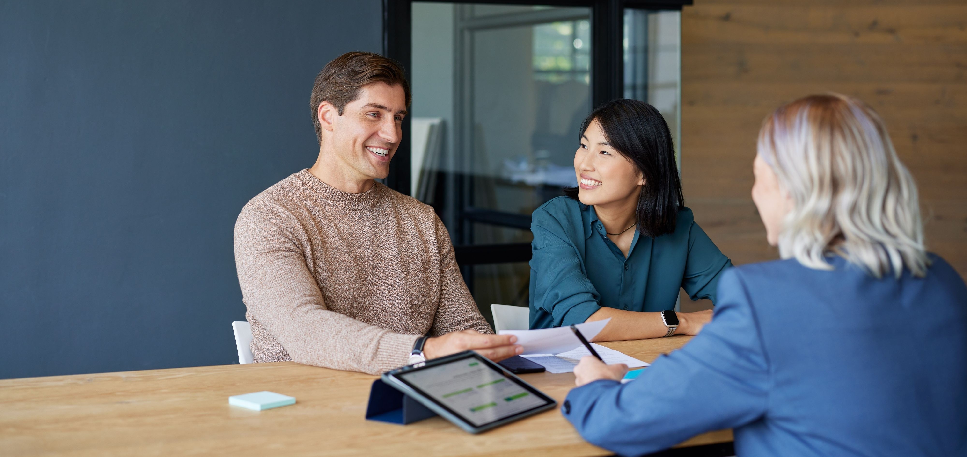 Smiling multiethnic couple receiving financial guidance from advisor with copy space. Financial agent discussing investment strategies with clients. Asian woman and his boyfriend consulting with professional for financial planning: savings and investments concept. 