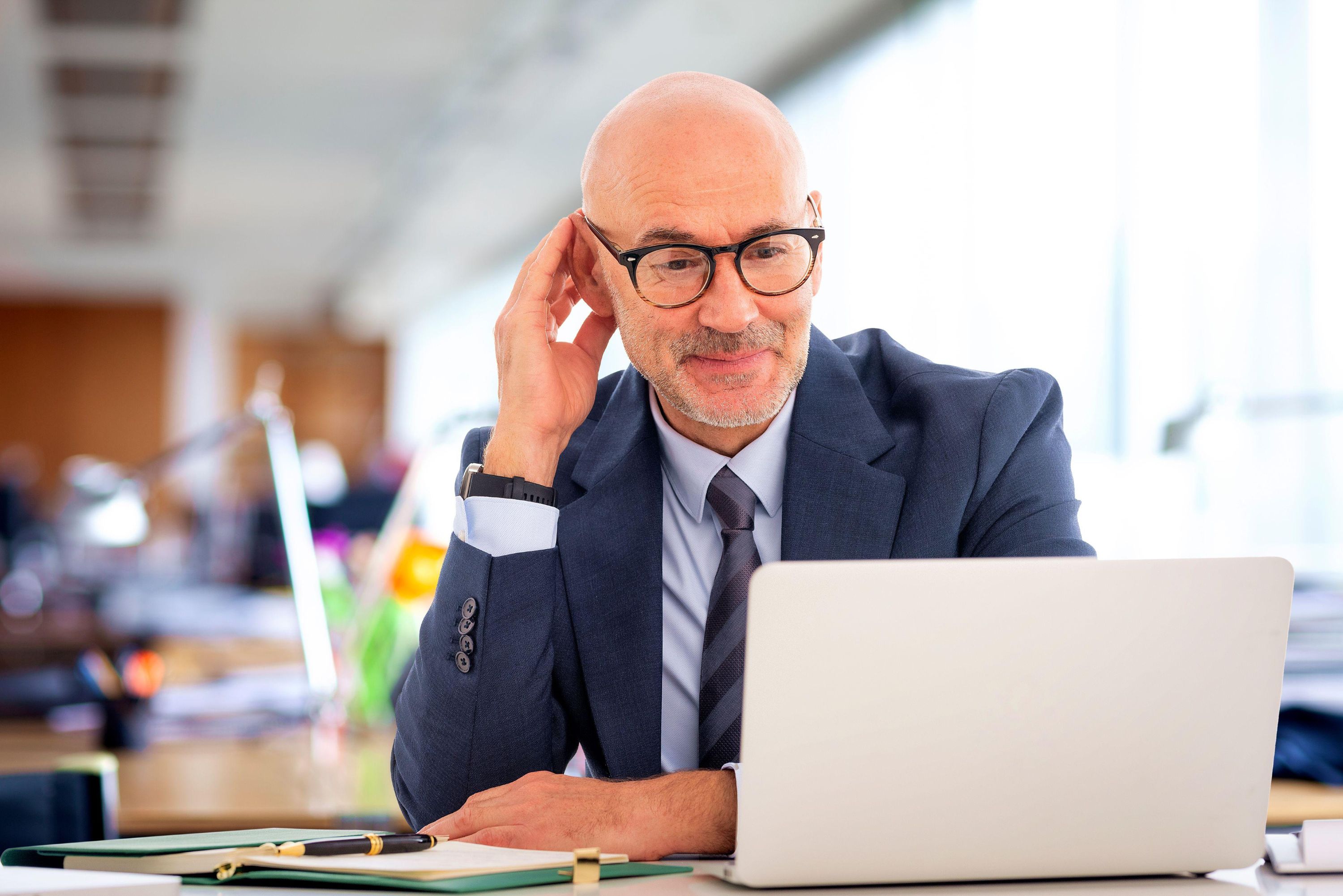 Senior businessman sitting at the office. Professional male using laptop for work and having web conference. 