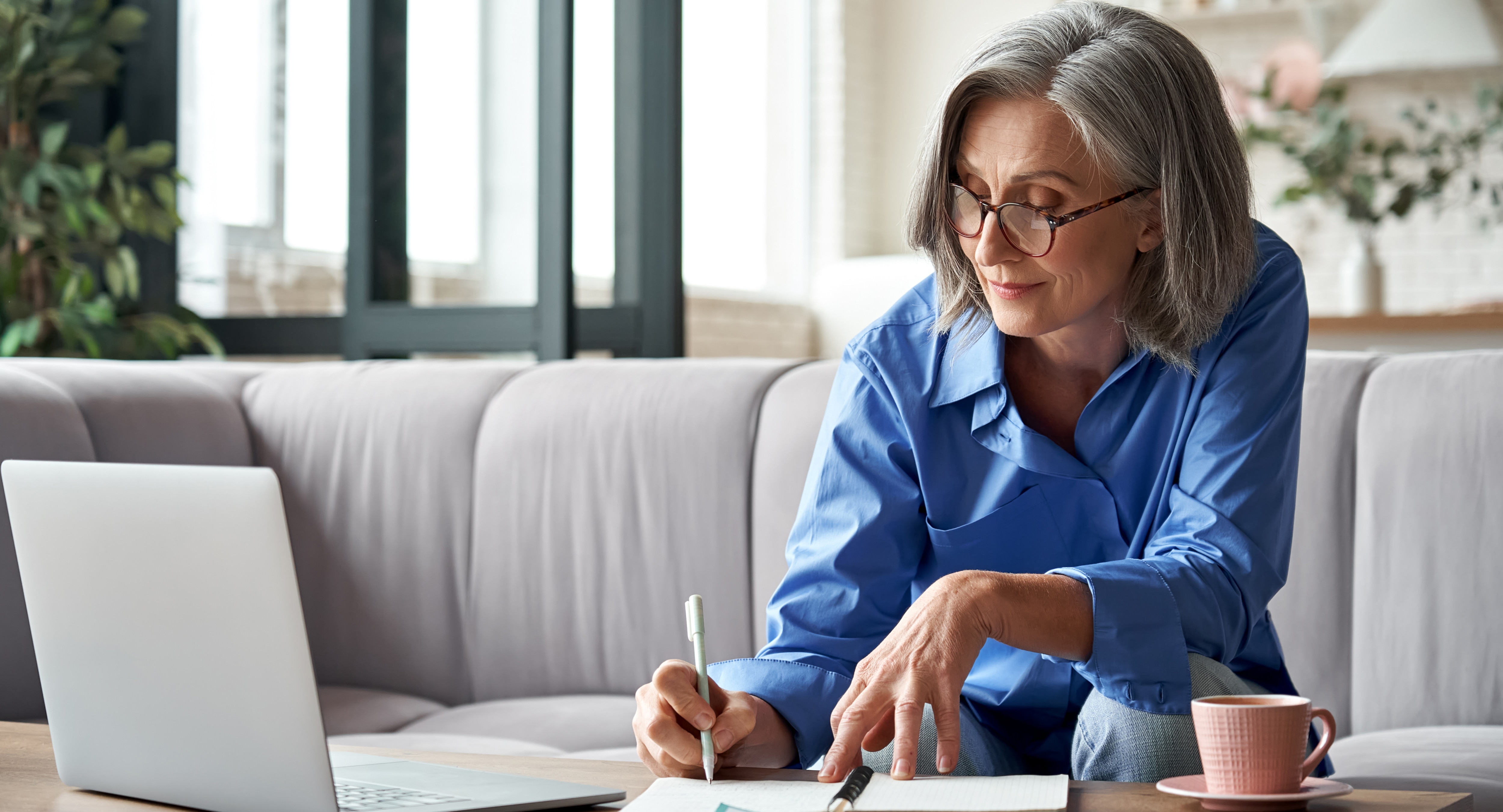 Woman sitting in front of laptop, writing