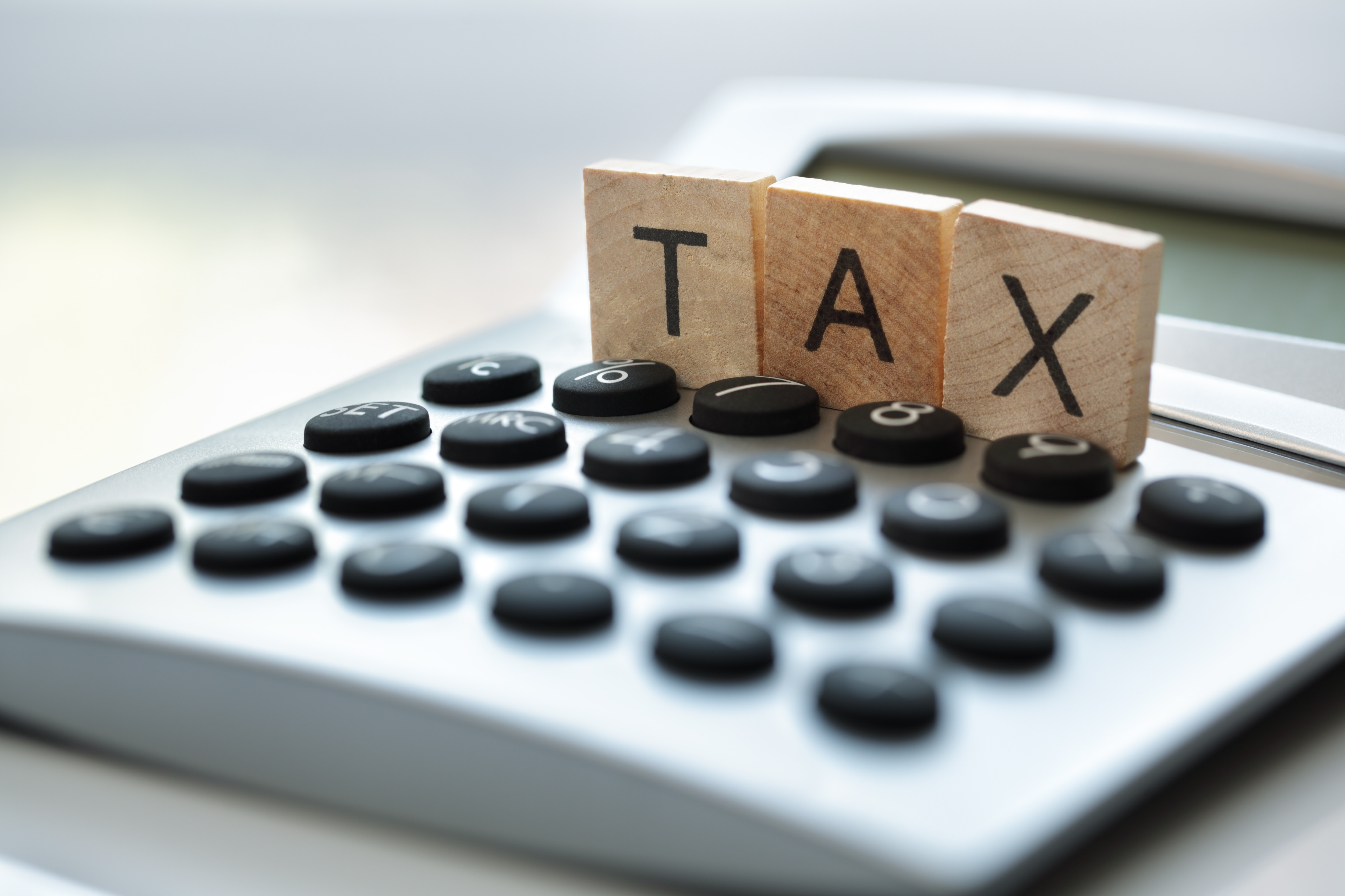 Calculator with the word tax written in wooden block letters
