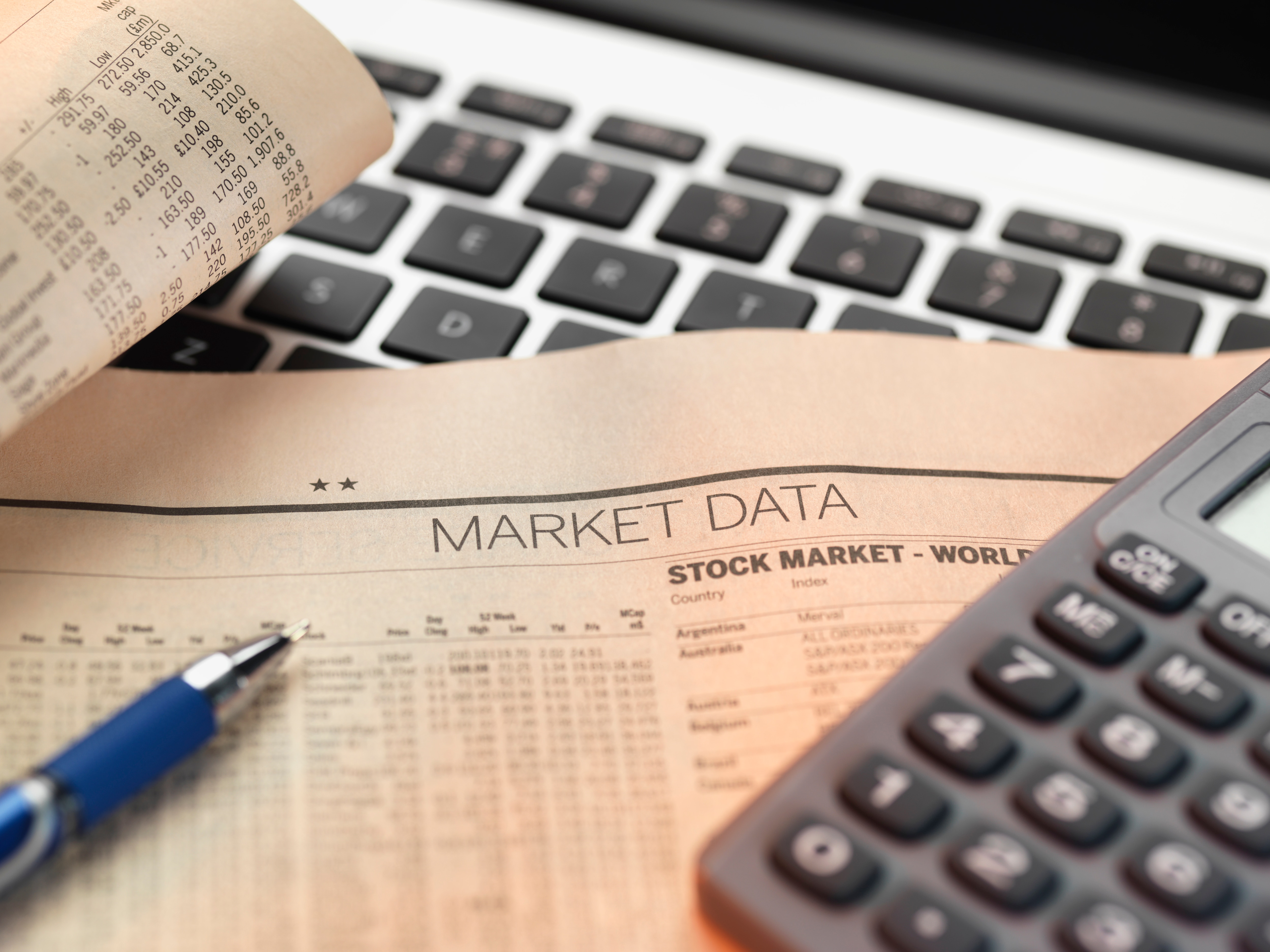 Calculator, newspaper with market data, and computer keyboard