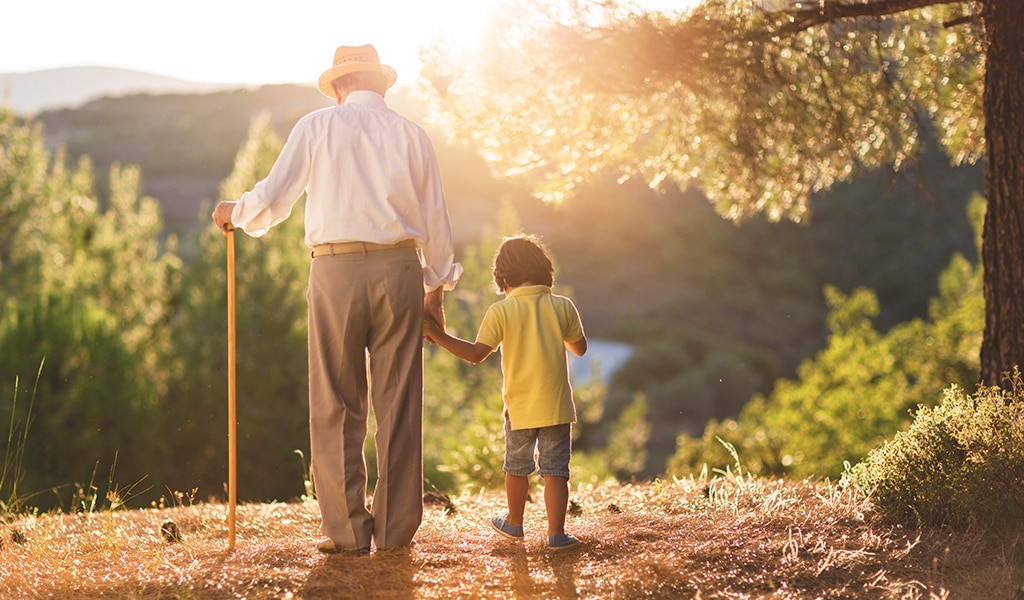 Grandfather and grandson walking hand in hand into the sunset