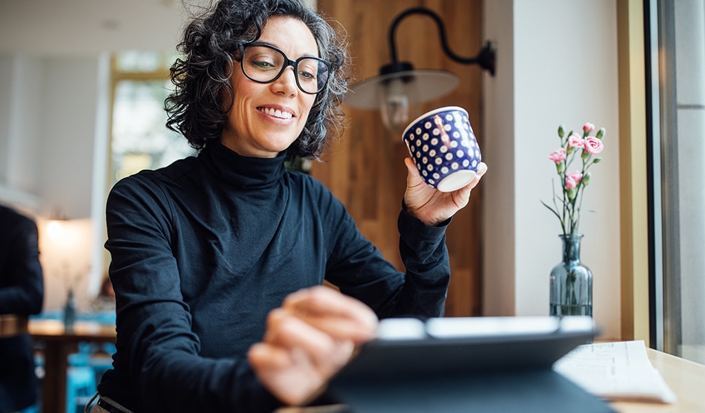 Woman on laptop sipping coffee