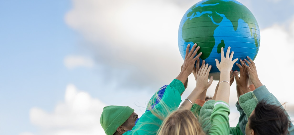 Group of people holding up a large globe