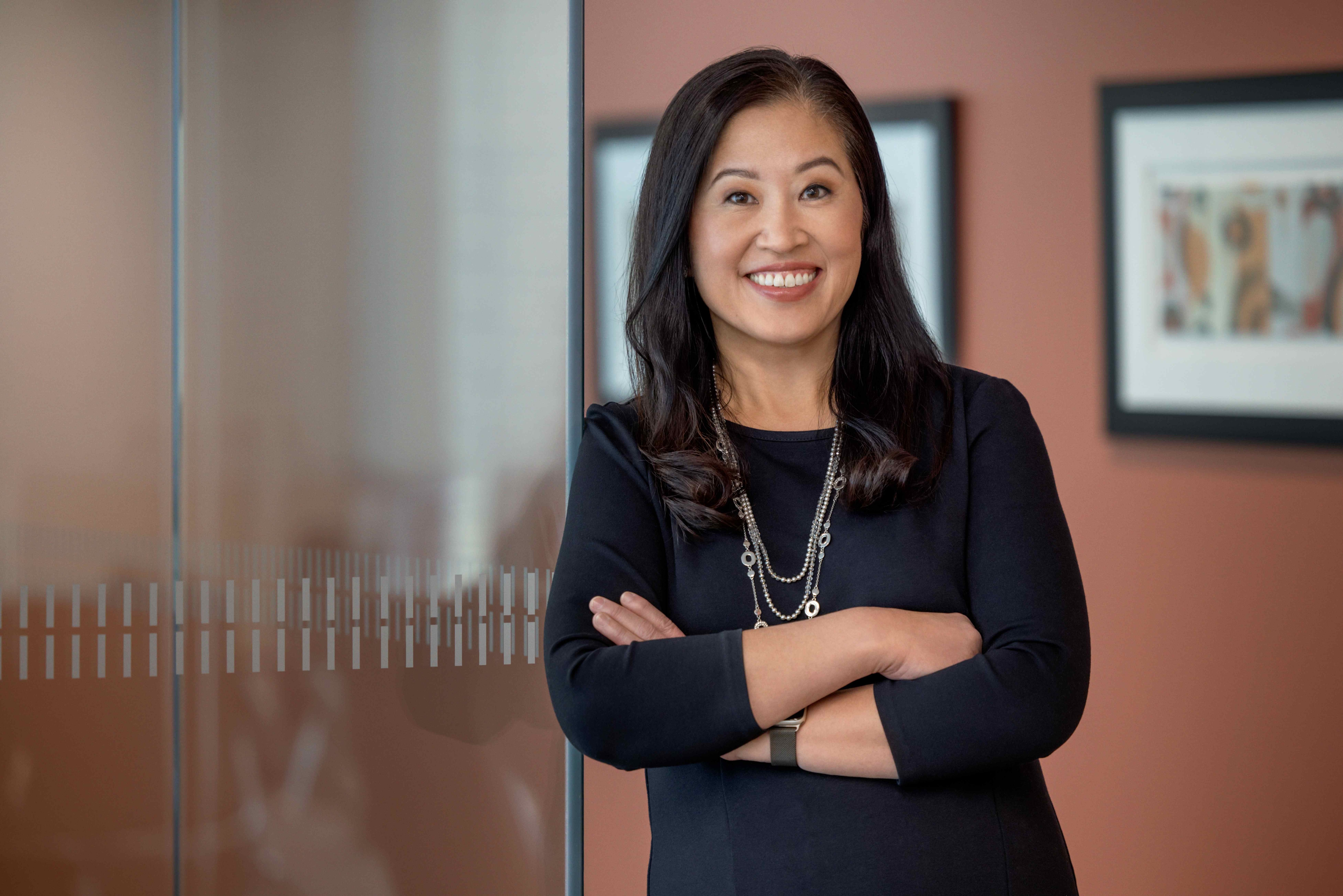 Woman smiling and leaning against her office door.