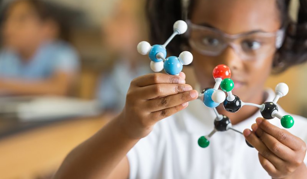 Young girl building a model of a molecule for science class