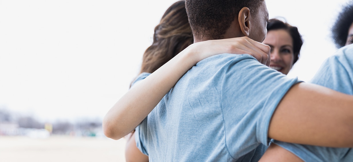 Volunteer group hugging in a circle and smiling 