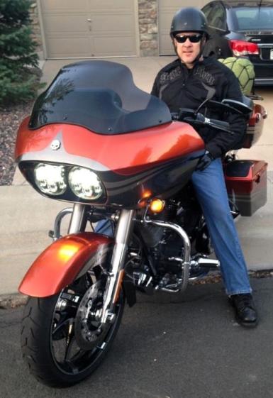 Man sitting on a parked red motorcycle.