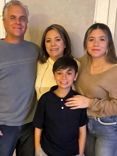 Gina taking a photo with her husband, Tom, and two children, Mia and Matthew