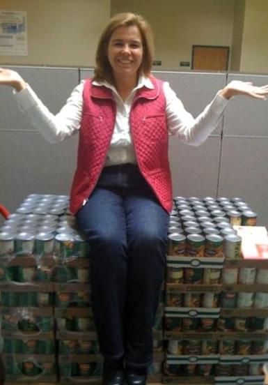 Woman sitting on a pallet of donated canned food