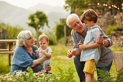 Grandparents and grandchildren kneeling in grass