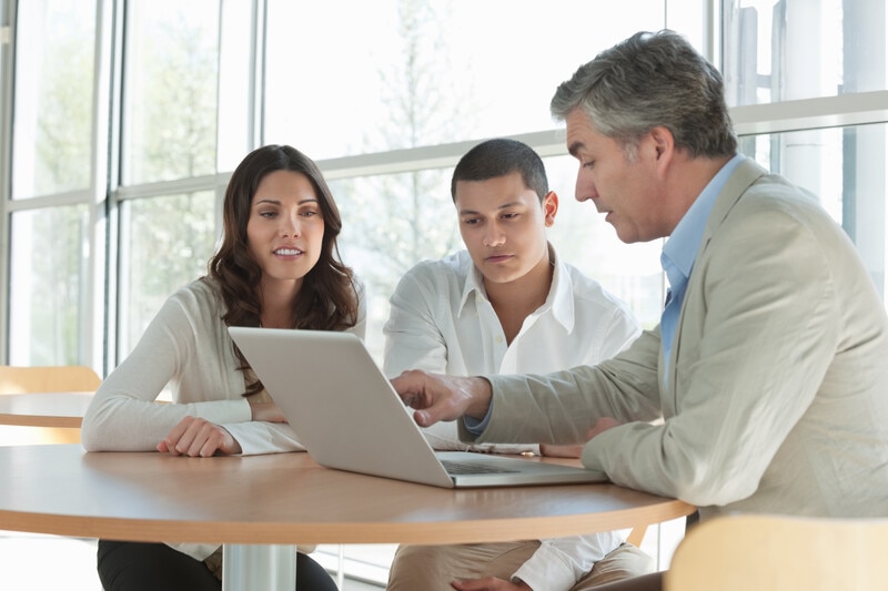 three people looking at a laptop 